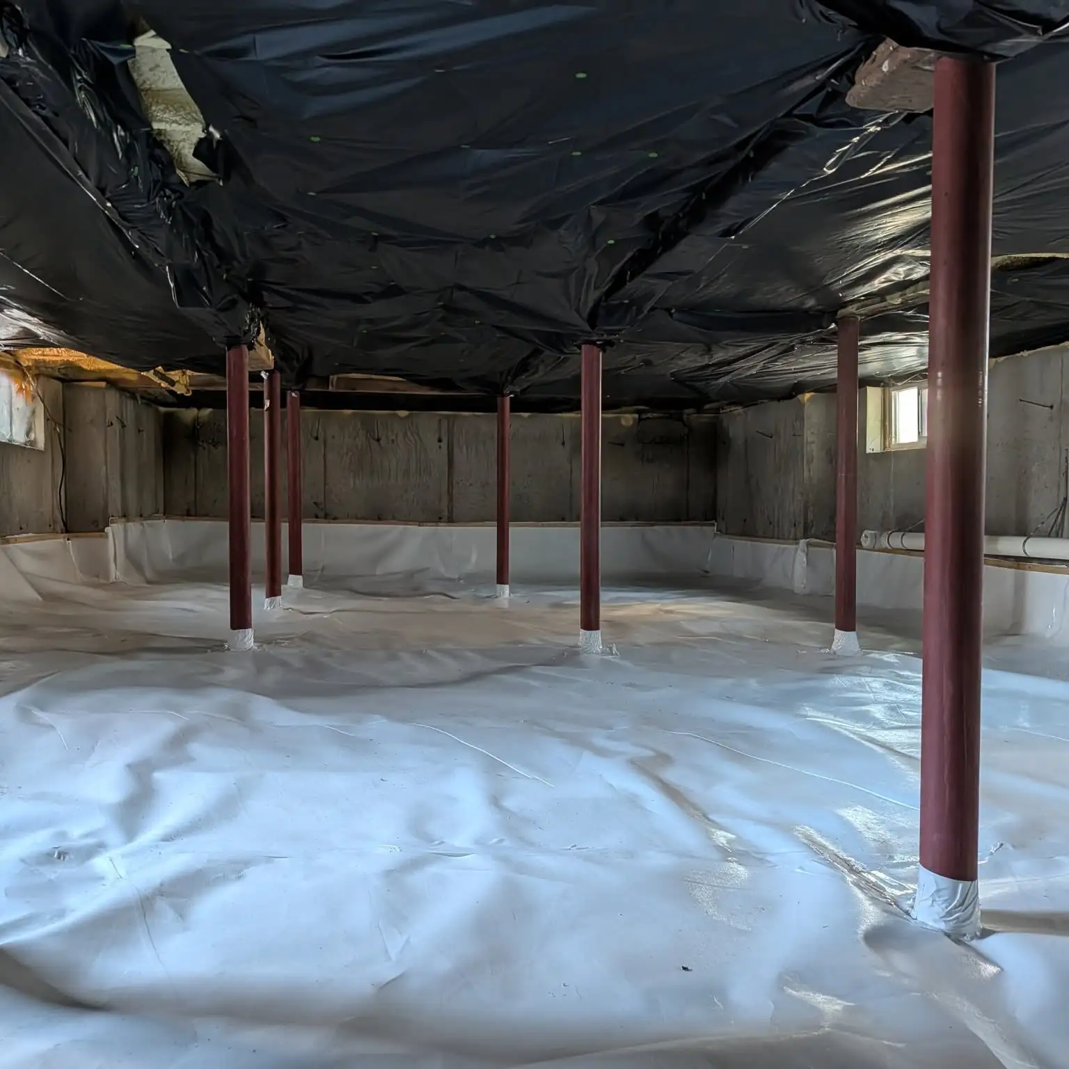 Crawl space fitted with a sealed floor moisture barrier around support posts
